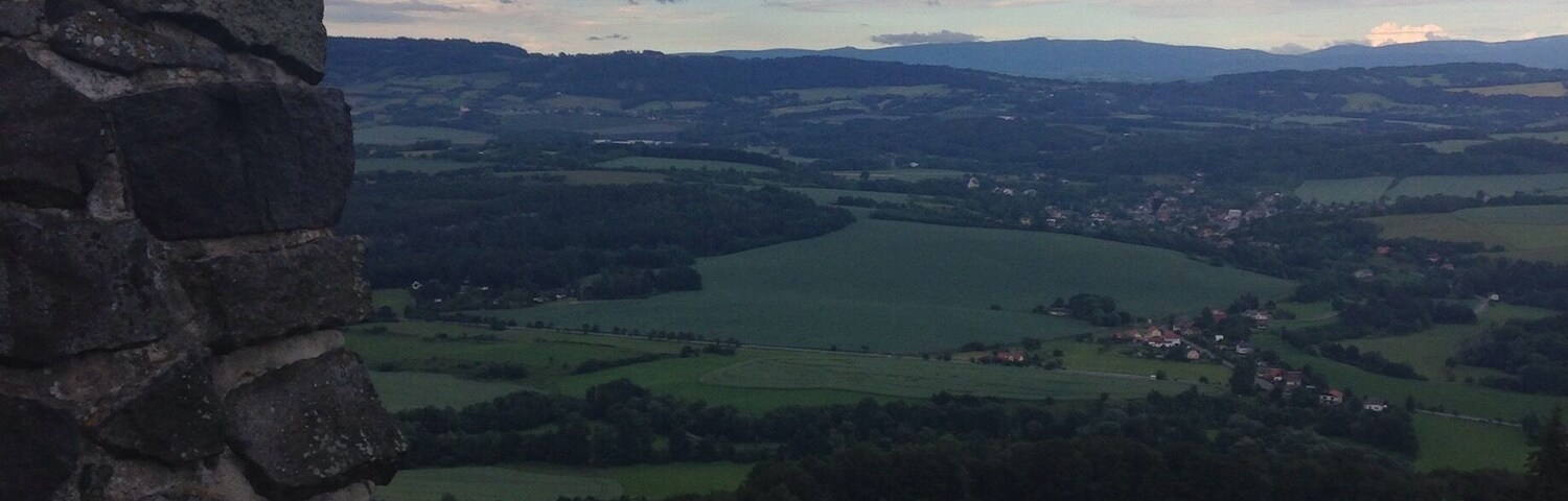 A stone wall overlooking a valley with fields and distant mountains.