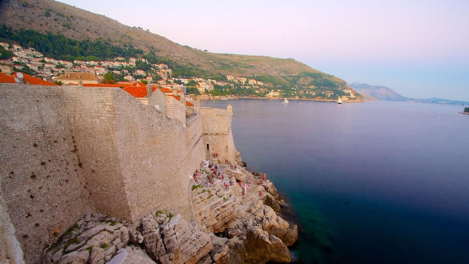 A coastal city with a historic stone wall and red-roofed buildings.