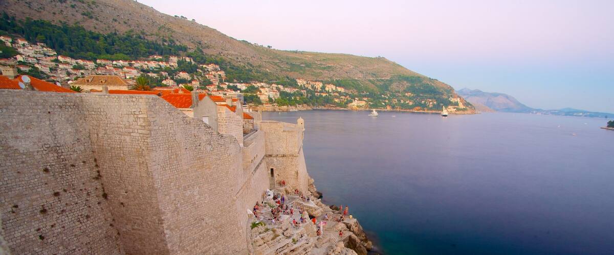 A coastal city with a historic stone wall and red-roofed buildings.