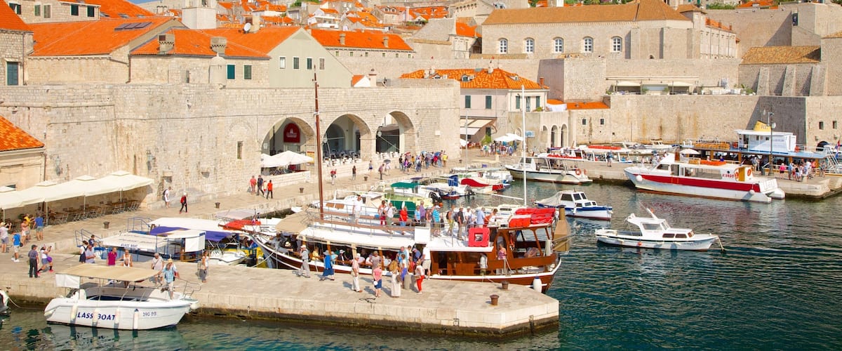 A harbor with boats, a stone building, and a hillside with houses.