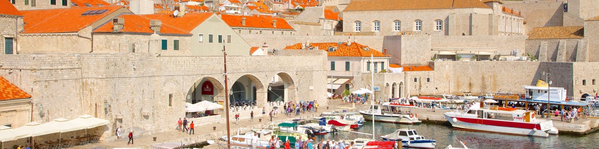 A harbor with boats, a stone building, and a hillside with houses.
