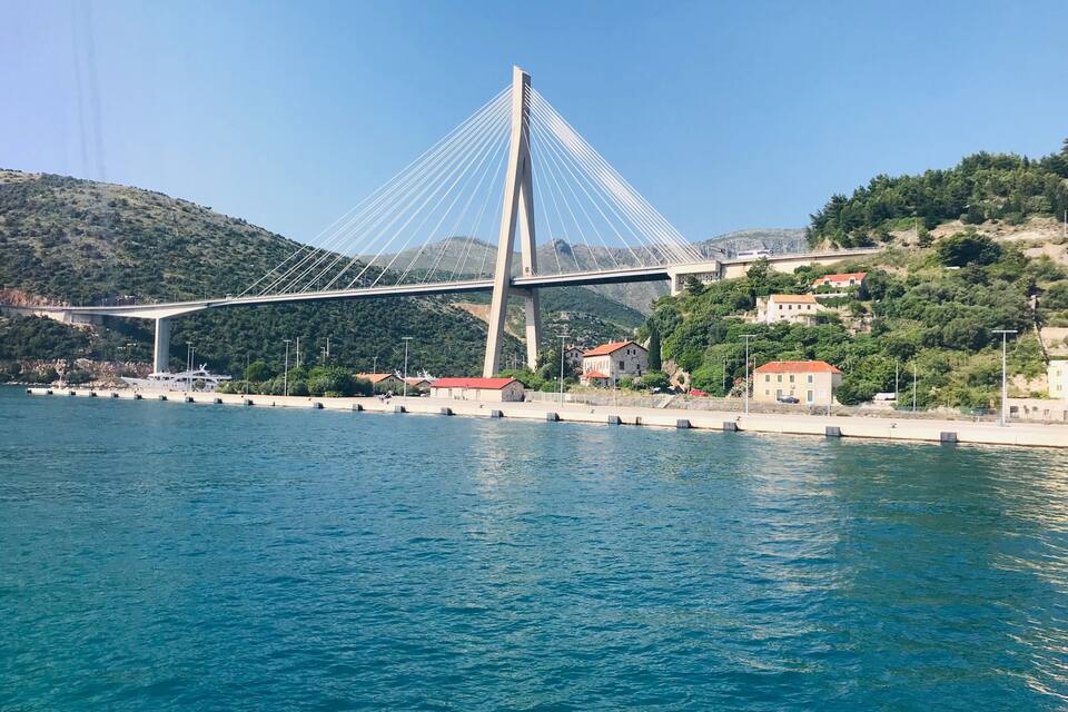 Un pont penjat sobre una massa d'aigua, amb una vessant de muntanya al fons.