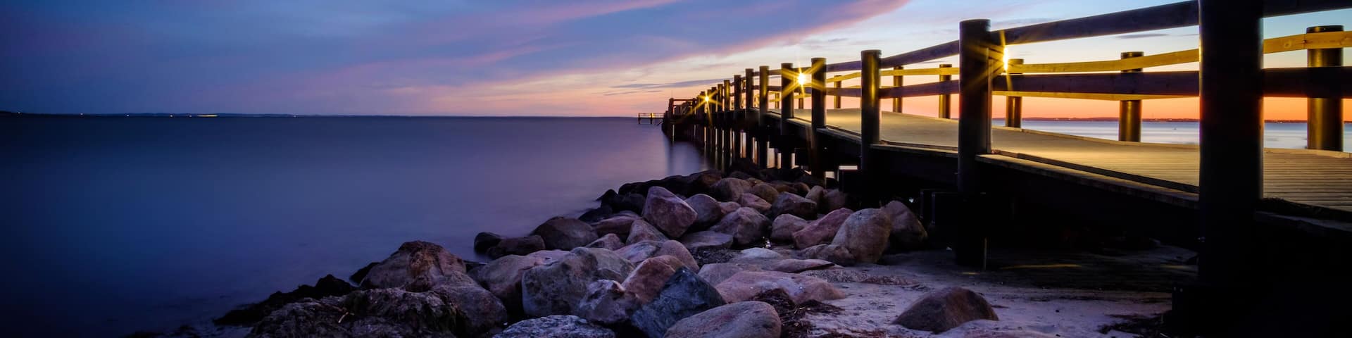 Sunset behind the pier at RydebÀck beach in Sweden