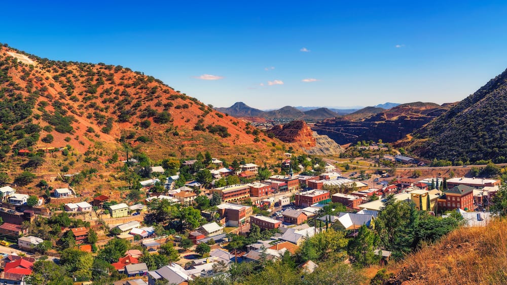 A town nestled in a valley surrounded by red hills and mountains.