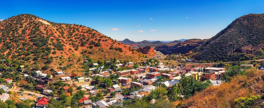 Un pueblo ubicado en un valle rodeado de colinas rojas y montañas.