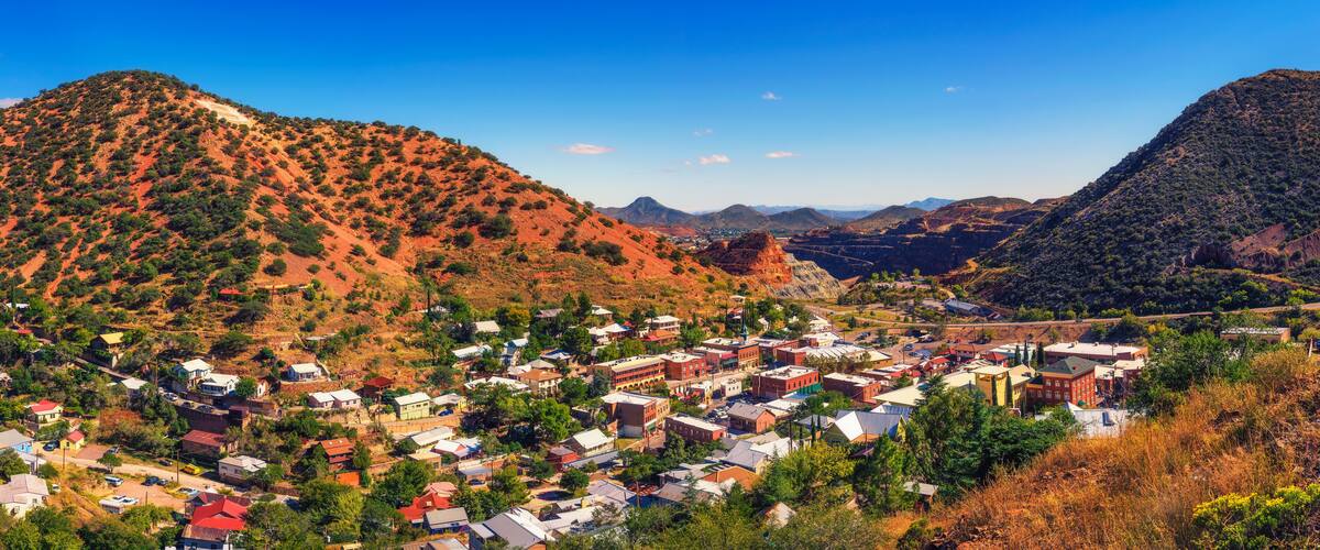 A town nestled in a valley surrounded by red hills and mountains.