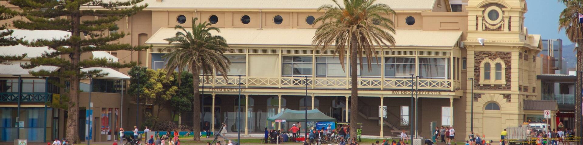 Un edificio histórico con una torre de reloj, palmeras y una multitud de personas.