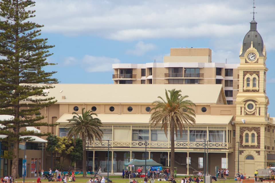 A historic building with a clock tower, palm trees, and a crowd of people.
