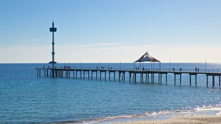 A pier extending into the sea with a lighthouse and a shaded pavilion.