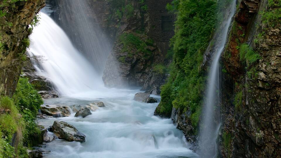A waterfall cascading down a rocky gorge surrounded by lush greenery.