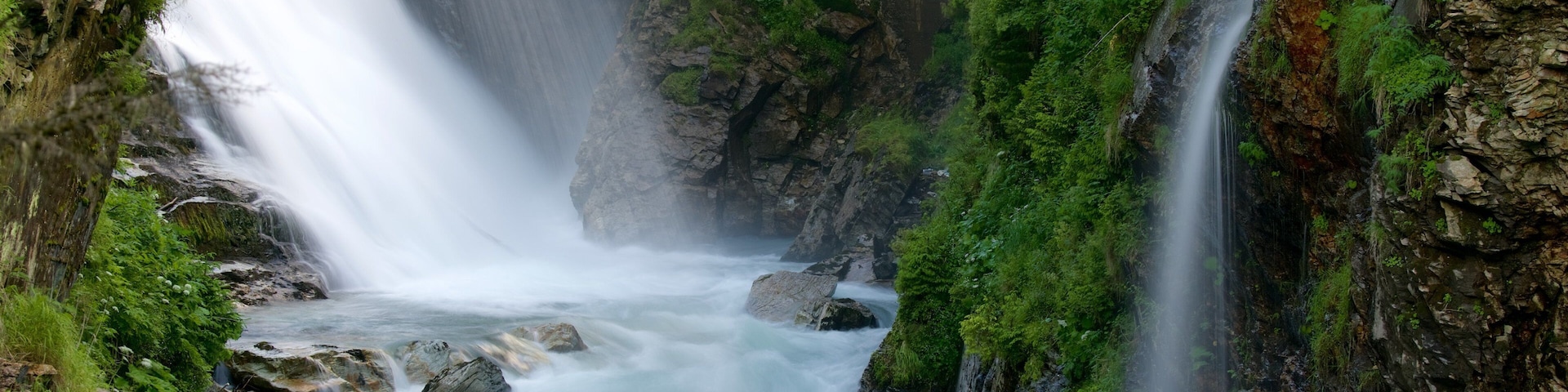 A waterfall cascading down a rocky gorge surrounded by lush greenery.