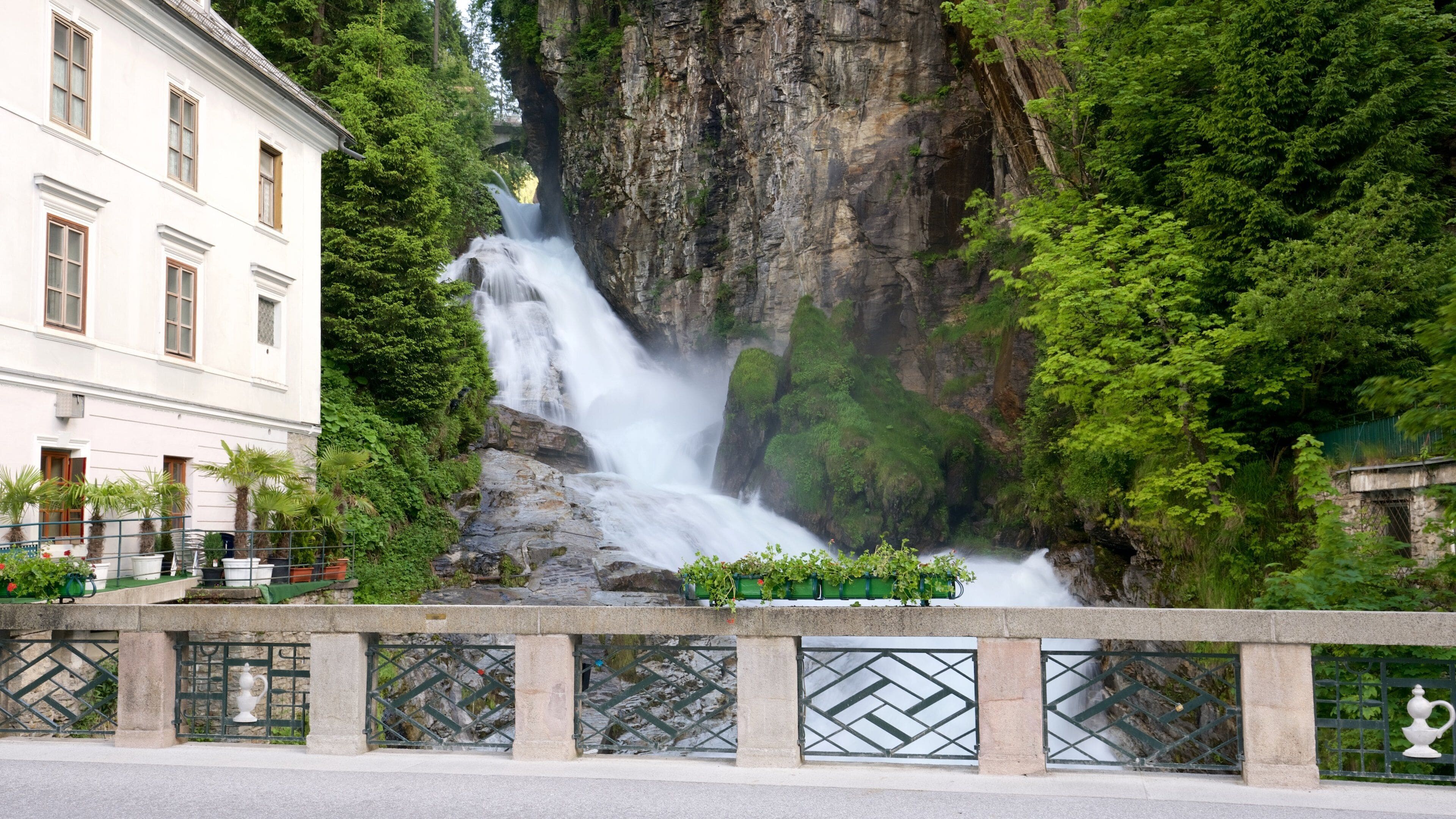 A waterfall cascading down a rocky cliff surrounded by lush greenery.