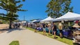 A sunny outdoor market with people browsing stalls under tents.