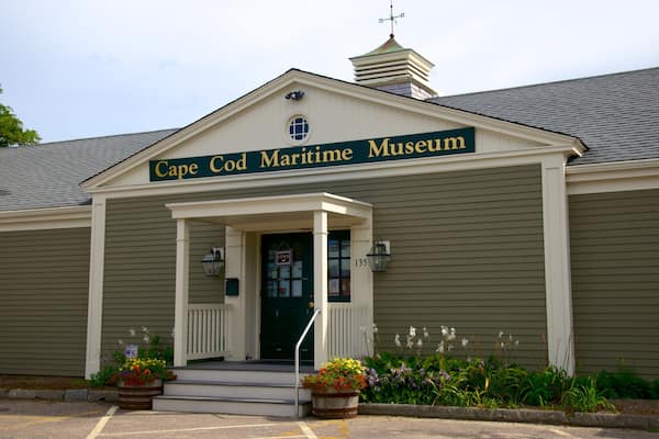 Cape Cod Maritime Museum med et grønt skilt, en hvid indgang og blomsterkasser.