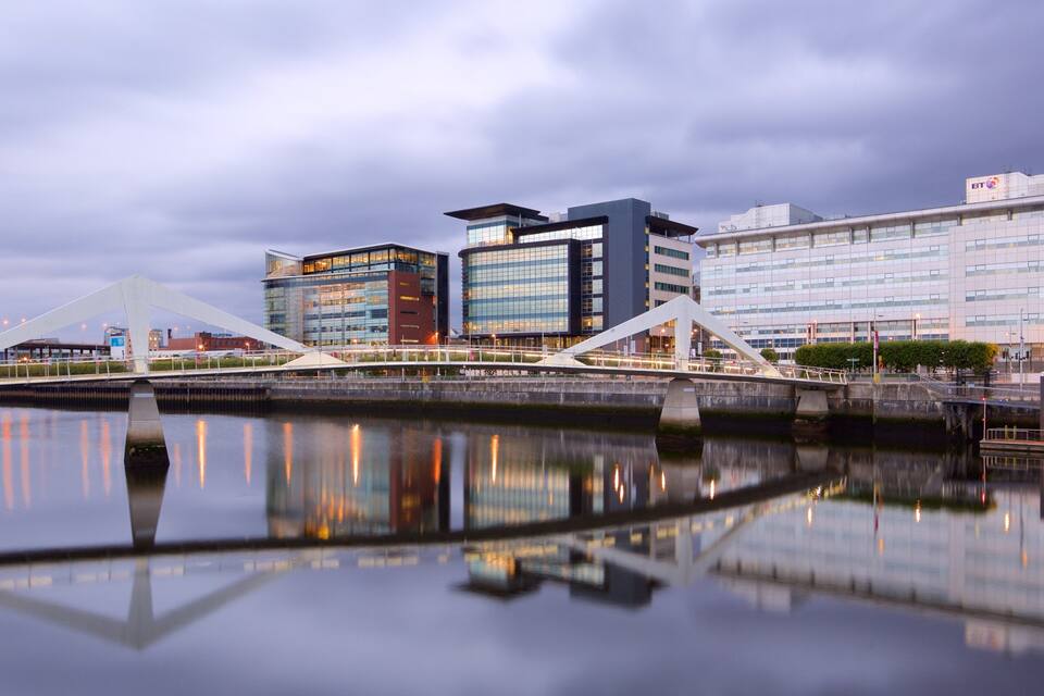 A modern cityscape with a river, a white bridge, and several contemporary buildings.