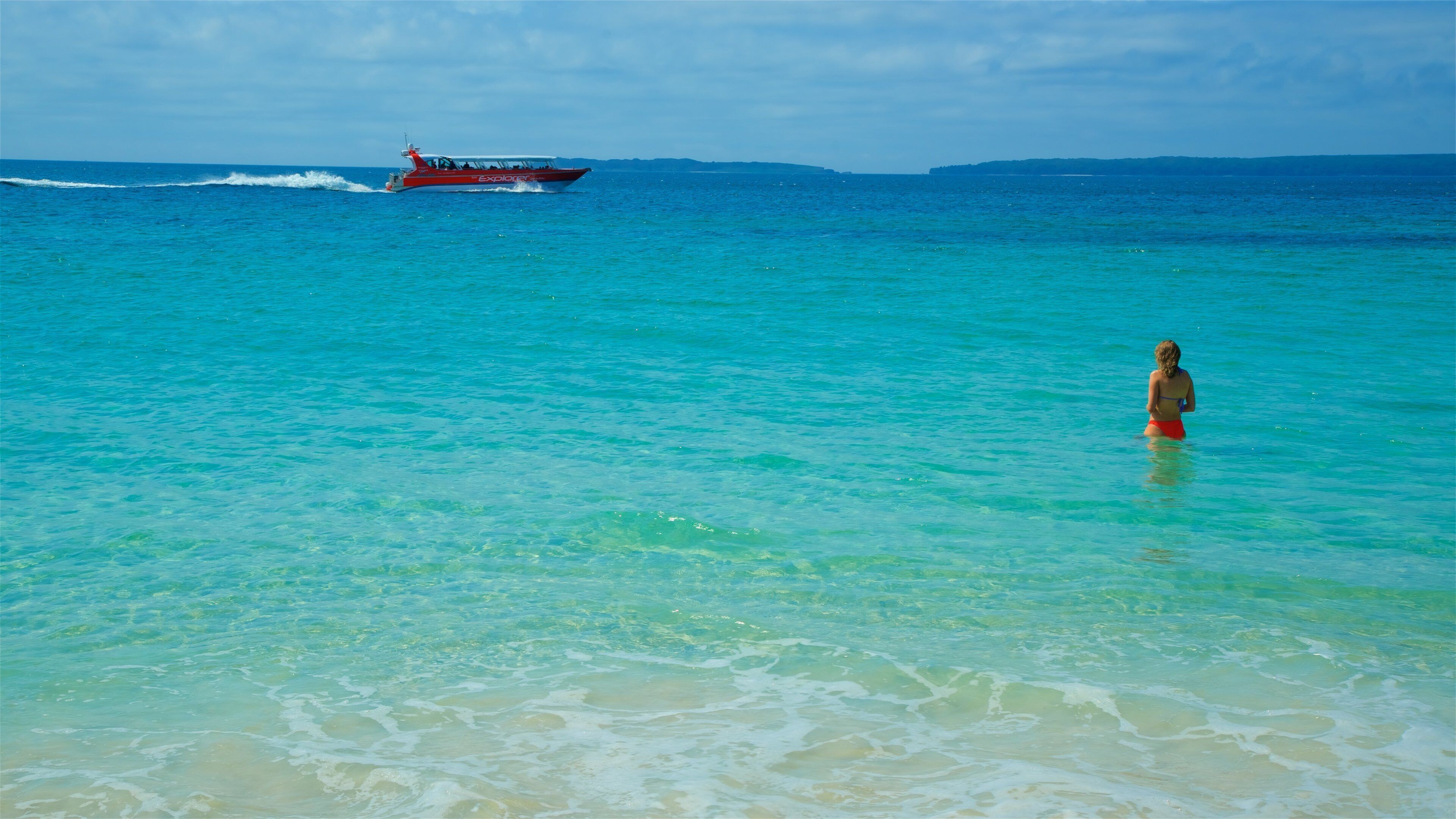 A clear turquoise sea with a boat named 'Explorer' and a person in the water.