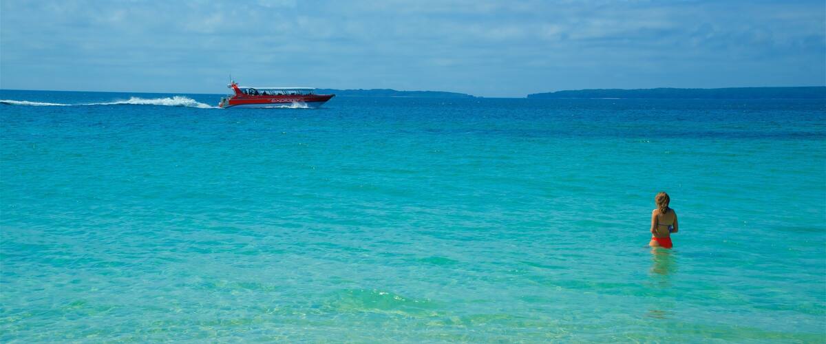A clear turquoise sea with a boat named 'Explorer' and a person in the water.