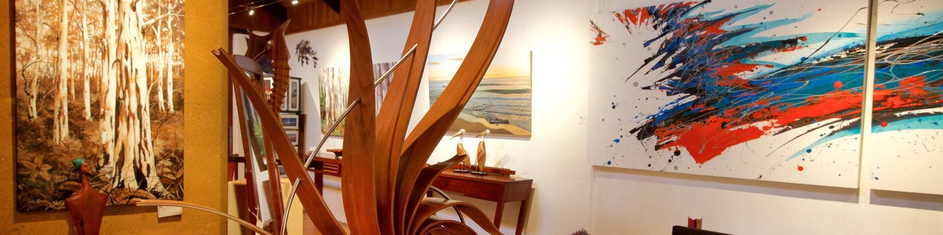 An art gallery with wooden sculptures and abstract paintings.