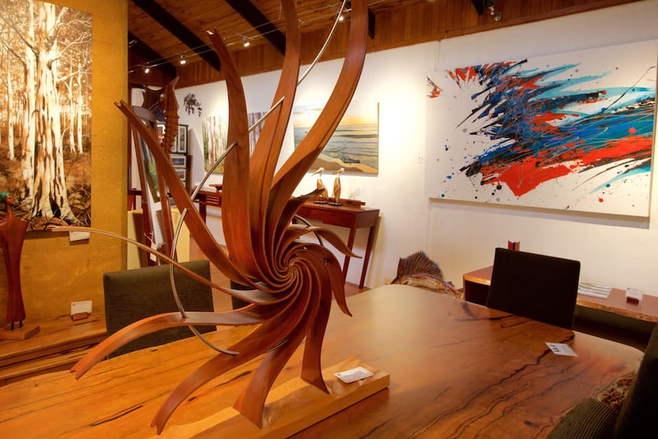 An art gallery with wooden sculptures and abstract paintings.