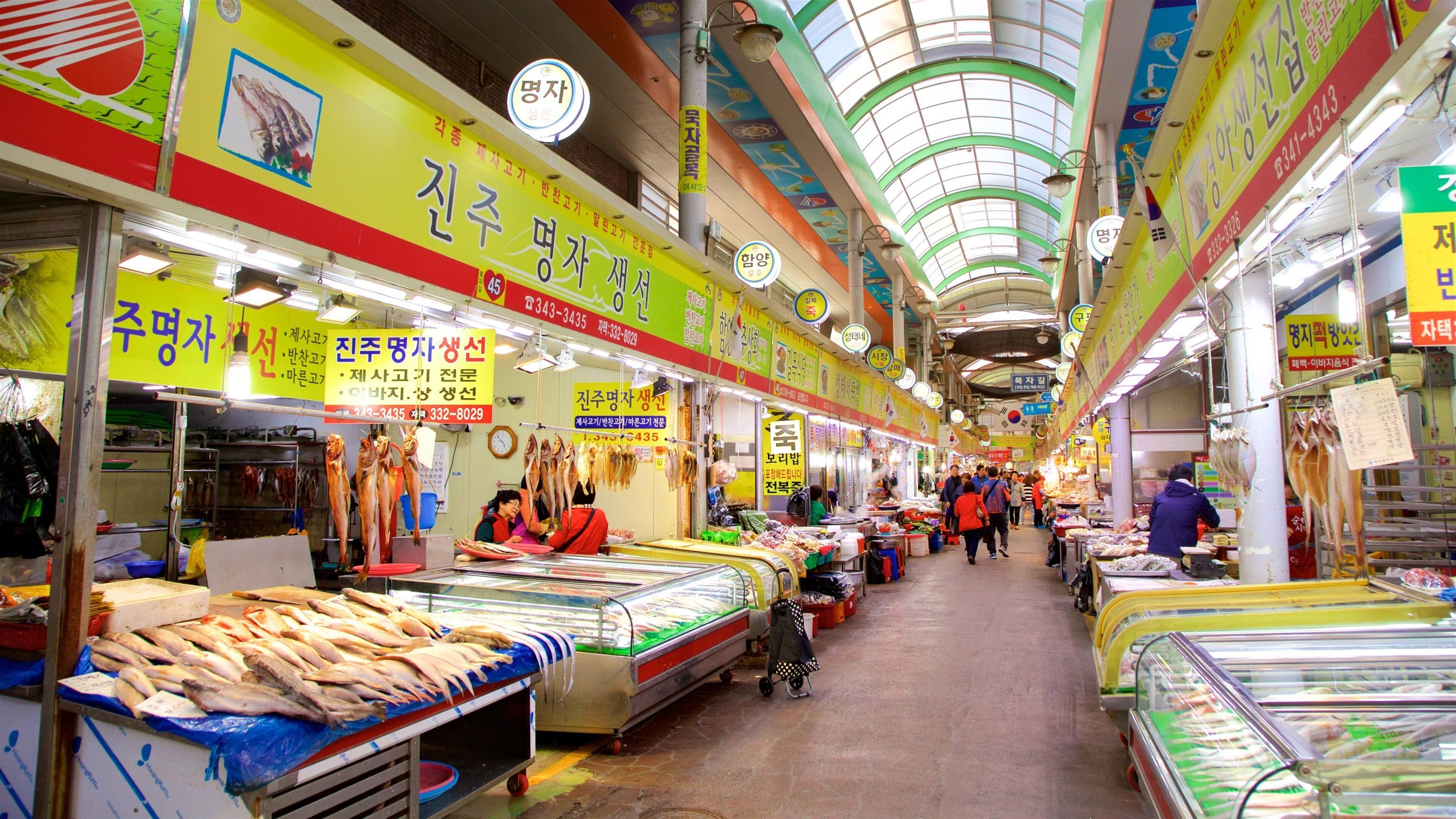 A busy indoor market with various stalls selling seafood and other goods.