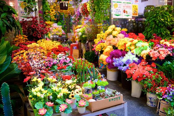 Un marché aux fleurs animé, où l’on trouve une grande variété de fleurs et de plantes aux couleurs vives.