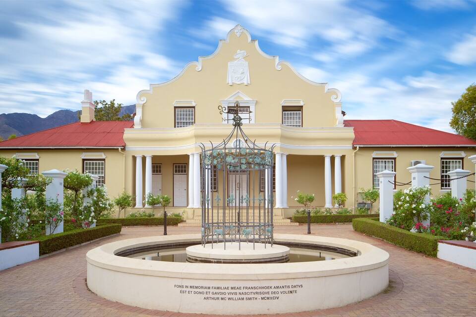 A stately building with a fountain in the center, surrounded by white columns and a red roof.