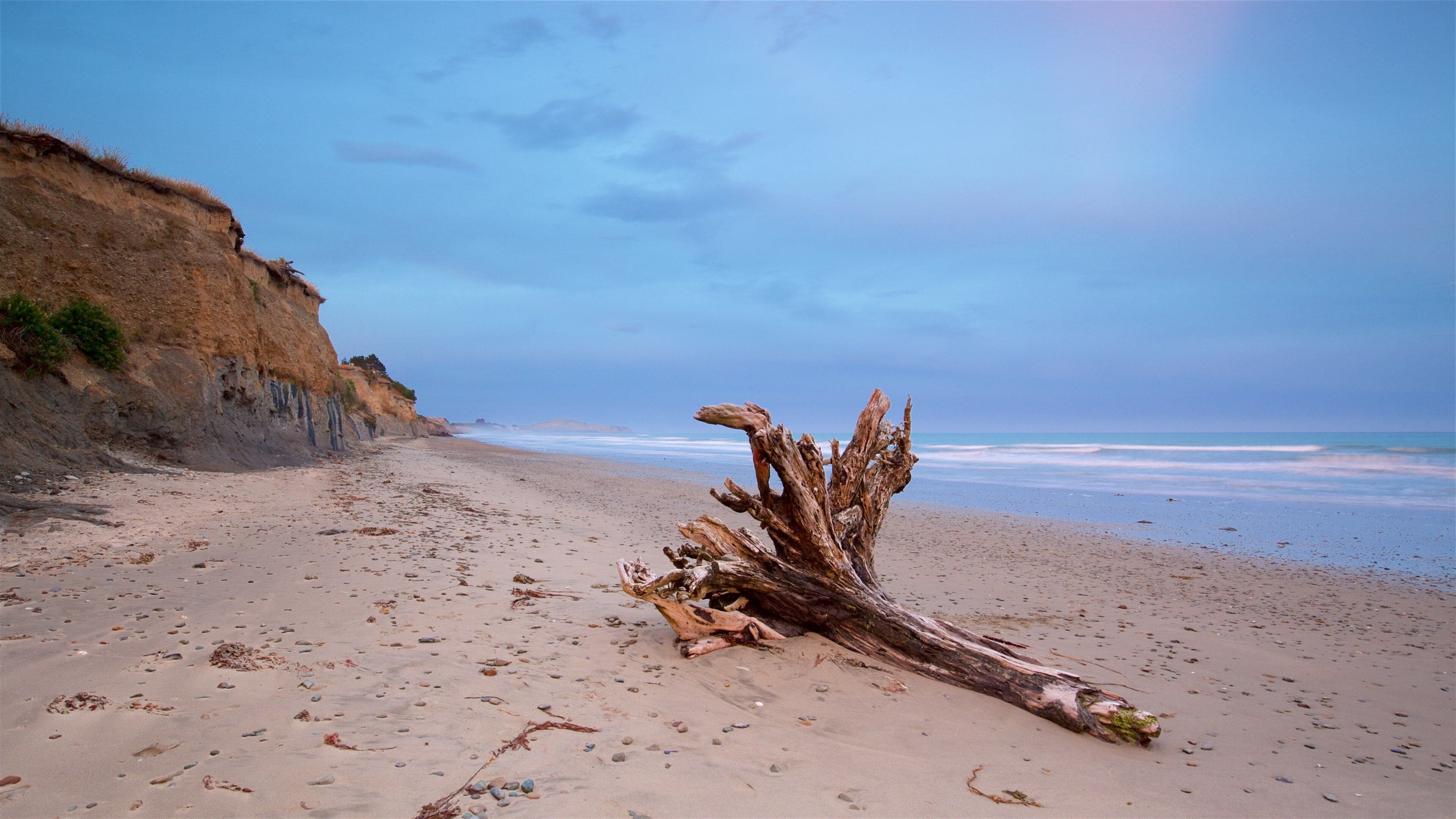 Oamaru que incluye una puesta de sol, una playa de arena y costa escarpada