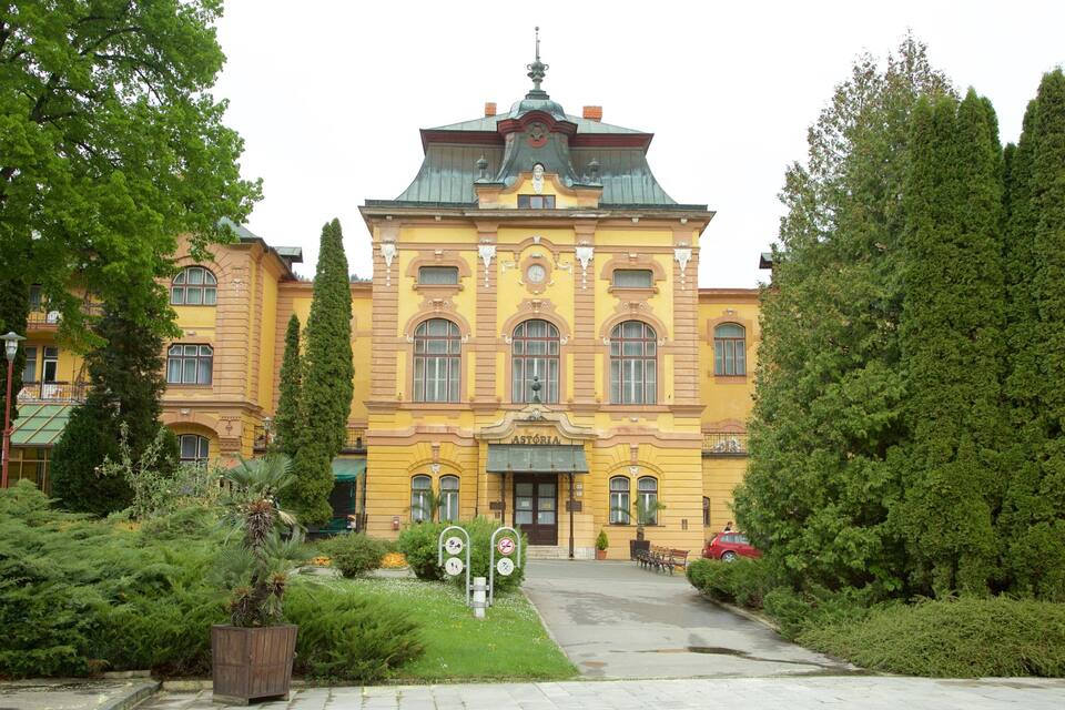 En gul byggnad med ett klocktorn, omgiven av grönska och träd.