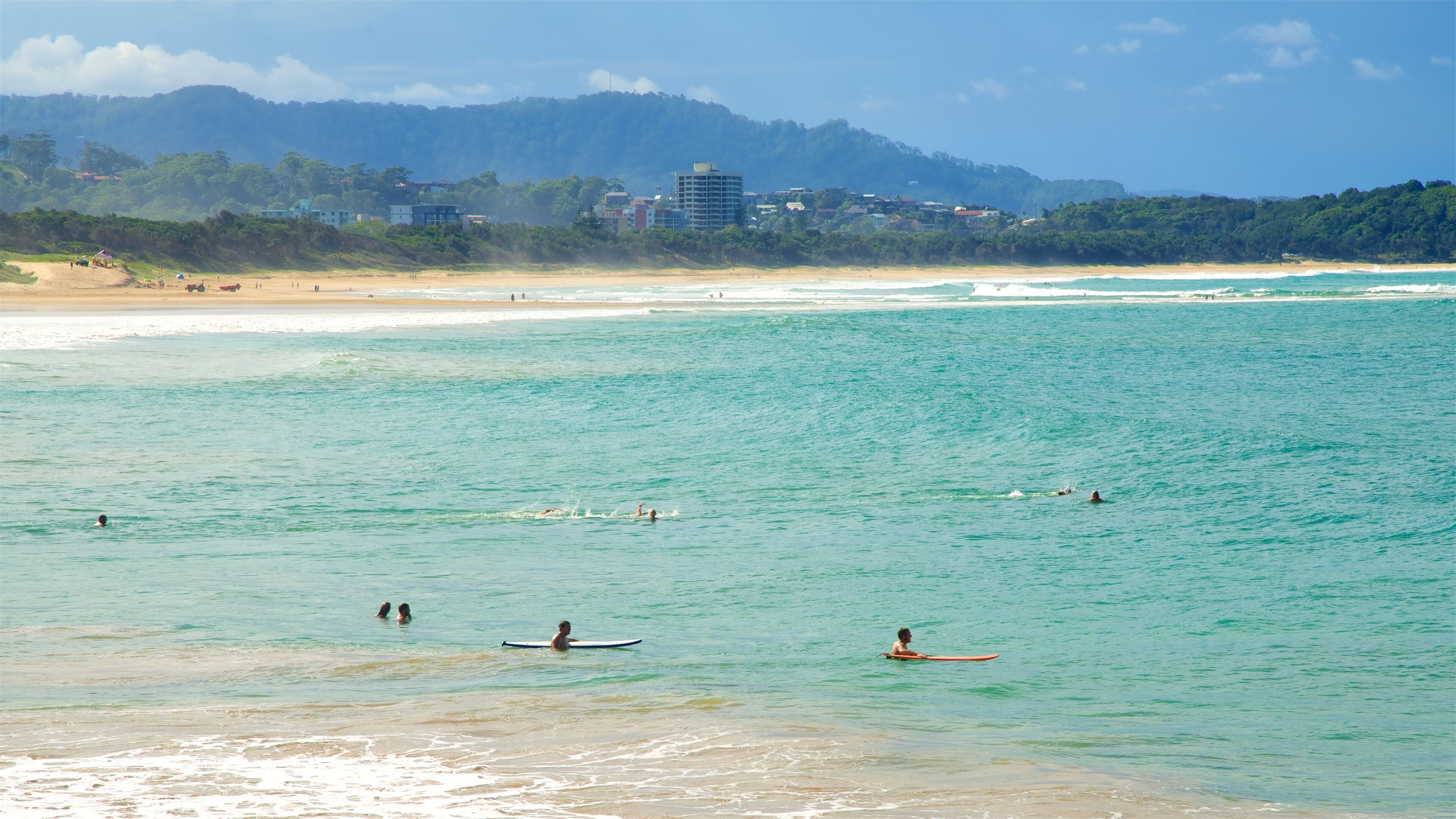 Coffs Harbour som visar bad och en sandstrand såväl som en stor grupp av människor