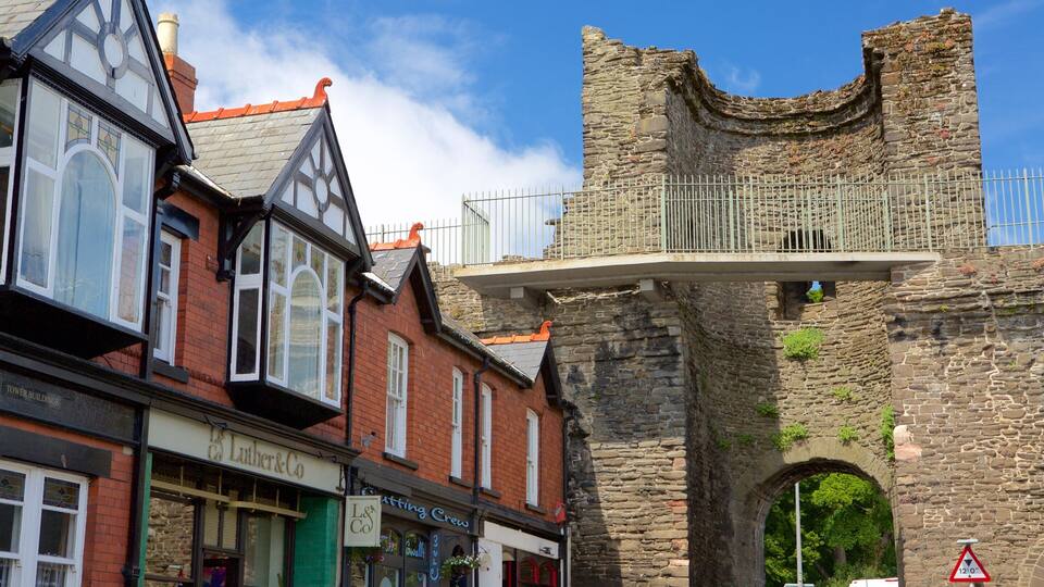 A historic stone tower with a balcony, adjacent to traditional buildings with signage for 'Luther & Co' and 'Atting Crew'.
