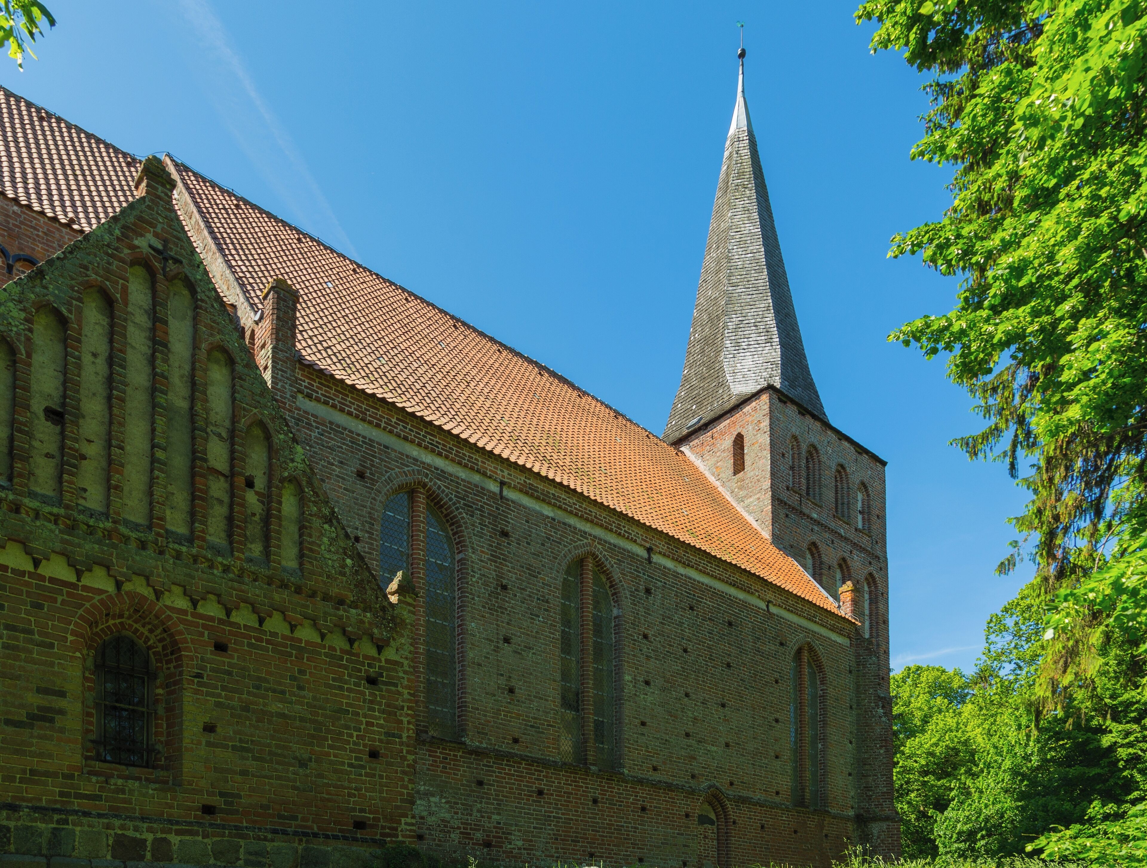 A historic church with a tall spire and a red-tiled roof.