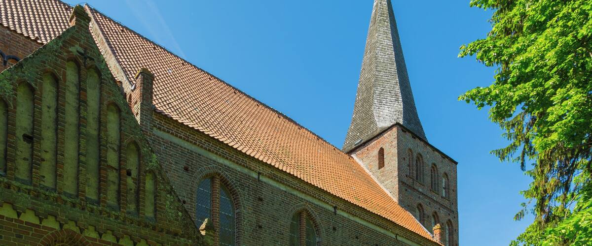A historic church with a tall spire and a red-tiled roof.