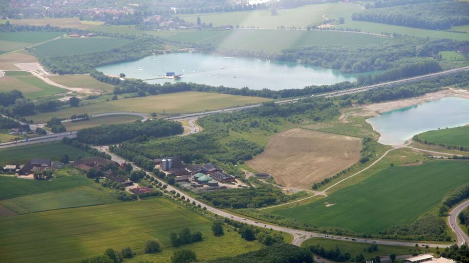 An aerial view of a rural landscape with multiple lakes, fields, and a few buildings.
