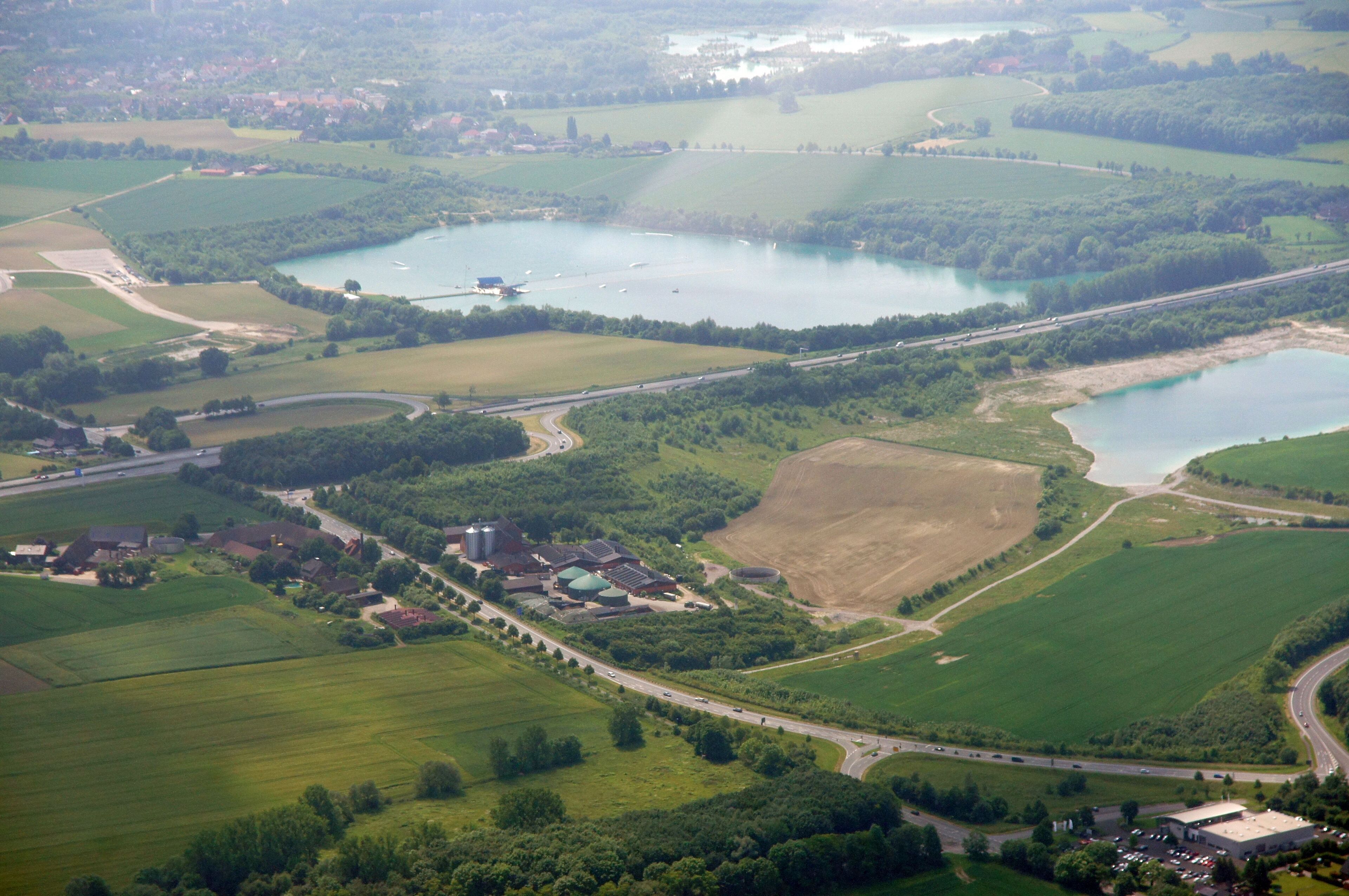 An aerial view of a rural landscape with multiple lakes, fields, and a few buildings.
