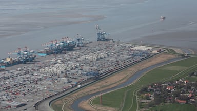 Un puerto industrial con contenedores de envío, grúas y una vía ferroviaria.