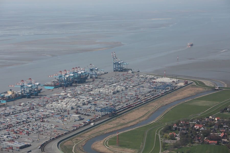 An industrial port with shipping containers, cranes, and a railway line.