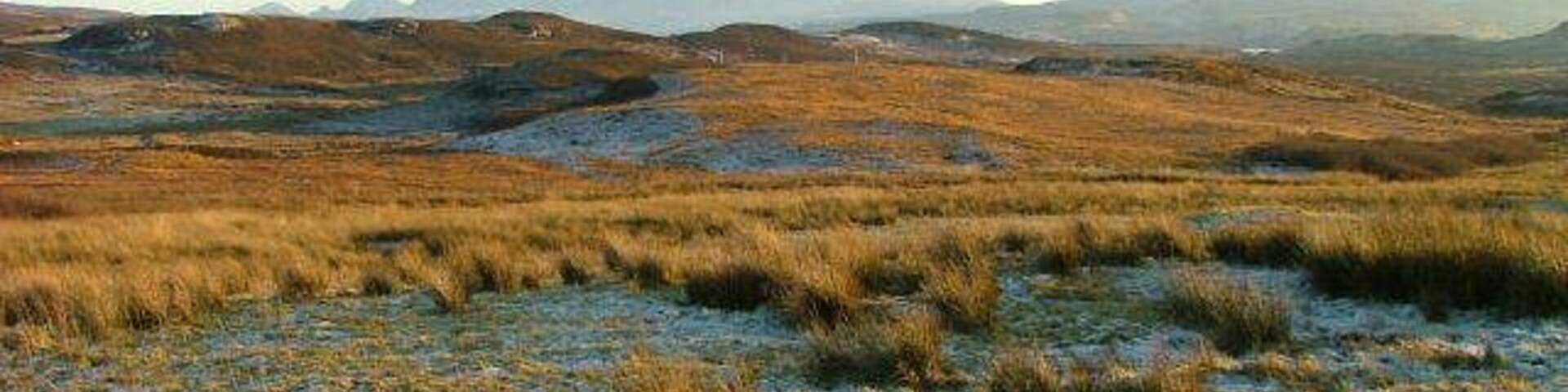 Paisagem com colinas ondulantes e montanhas ao longe.
