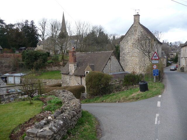 A rural road with stone walls, a church, and a school crossing sign.