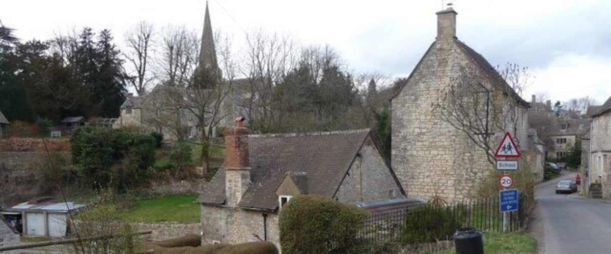 A rural road with stone walls, a church, and a school crossing sign.