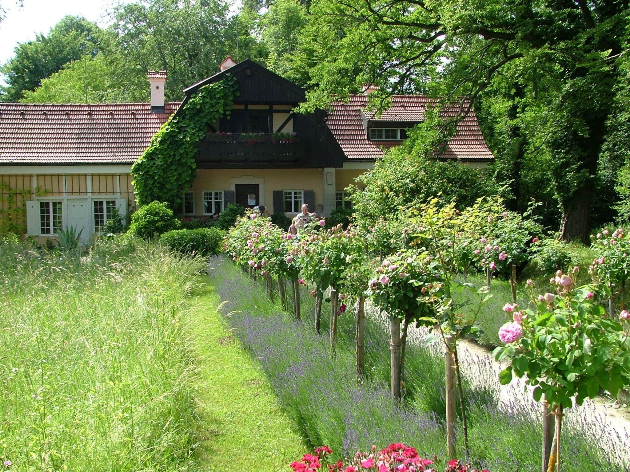 A traditional house with a tiled roof, surrounded by lush greenery and flowering plants.