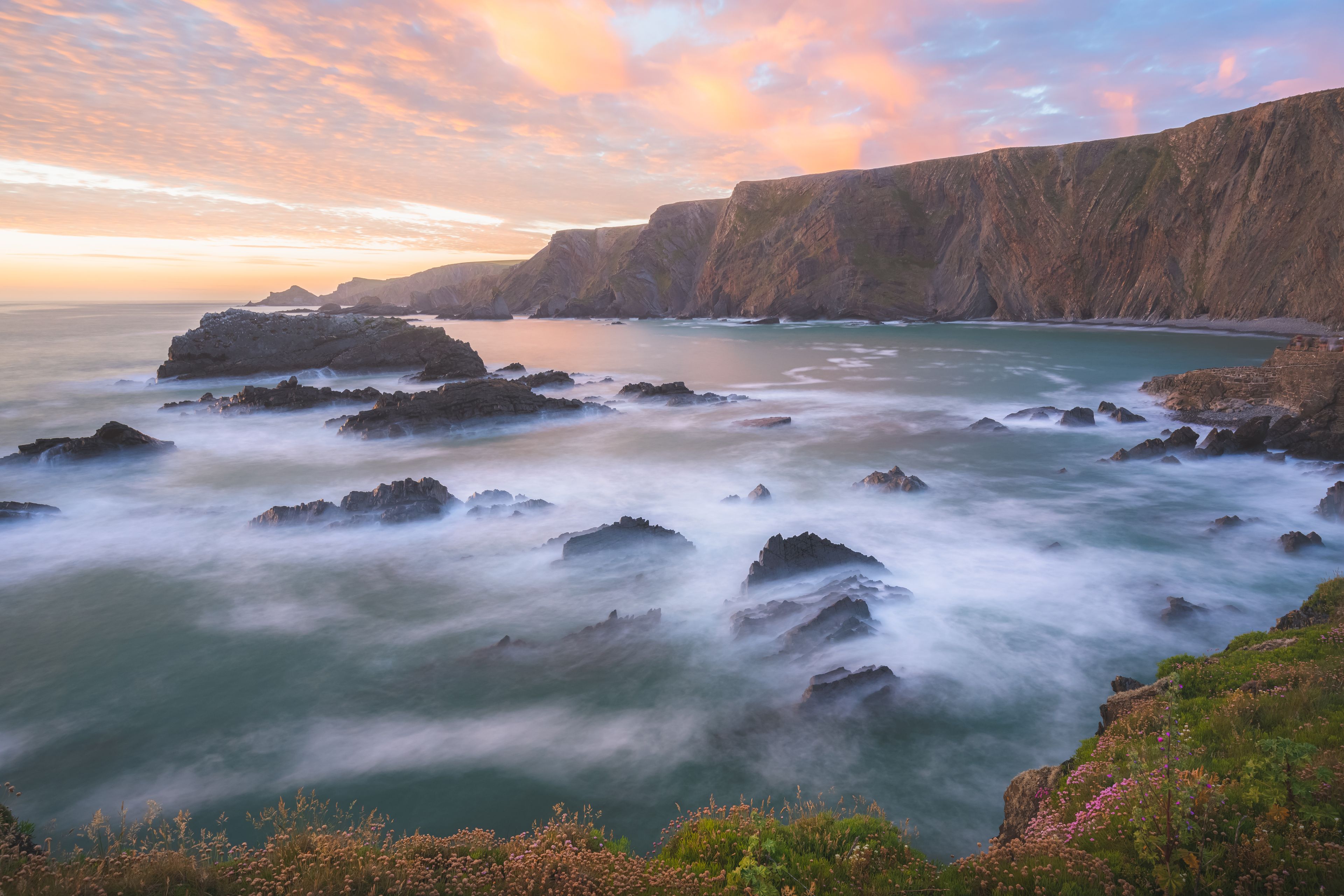 Dramatic seascape landscape of rock Atlantic coastline with colourful sunset or sunrise sky at Hartland Quay on the North Devon coast in England, UK.
