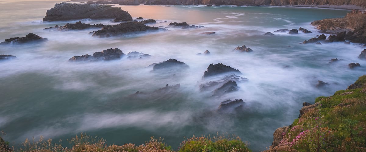 Un paisaje costero con acantilados rocosos y un mar tranquilo.