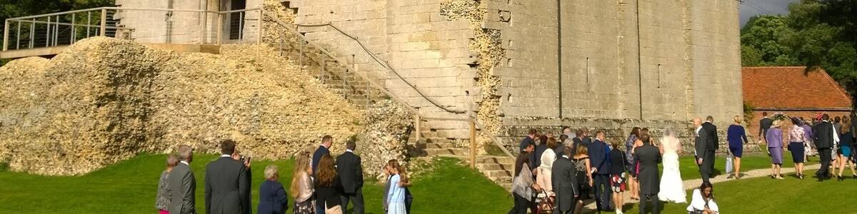 Eine historische Burg mit Wimpel, umgeben von einer grünen Wiese mit Personen.