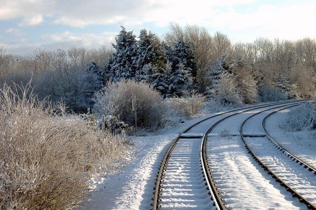 A snow-covered railway track curving through a forest.