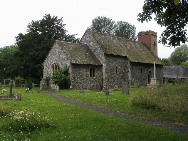 A stone church with a bell tower, surrounded by a cemetery and lush greenery.