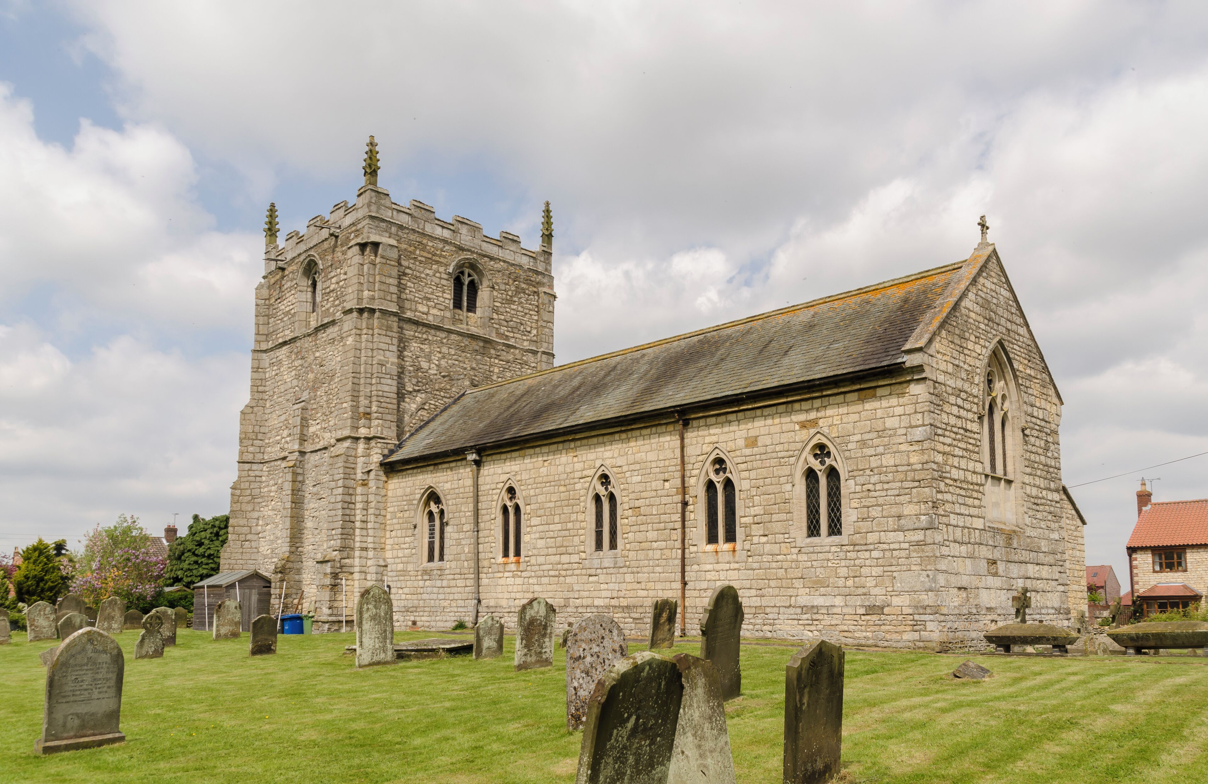A historic stone church with a bell tower and a cemetery in front.