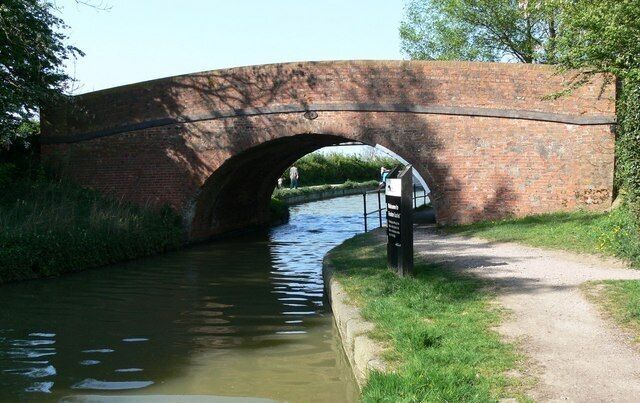 A brick bridge over a narrow canal with a path beside it.