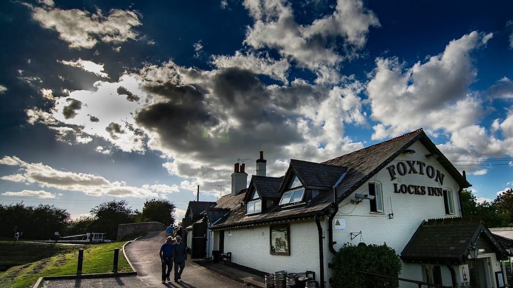 A white building with the sign "FOxton Locks Inn" on a sunny day.