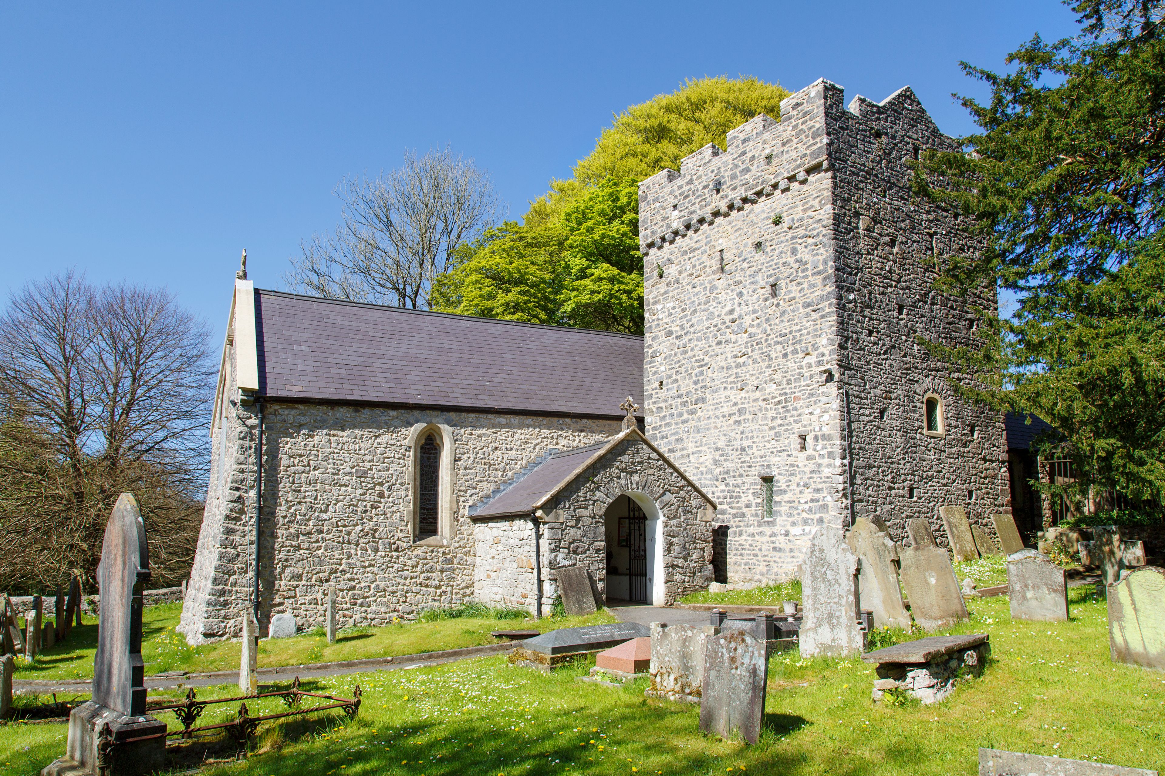 A stone church with a bell tower and a graveyard with headstones.
