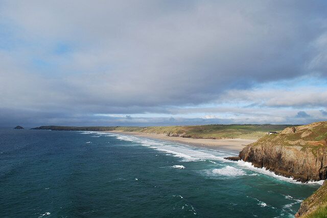 A coastal landscape with a beach, cliffs, and the ocean.